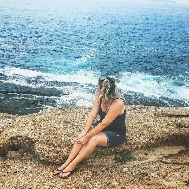 Allison sitting on rocks above the ocean